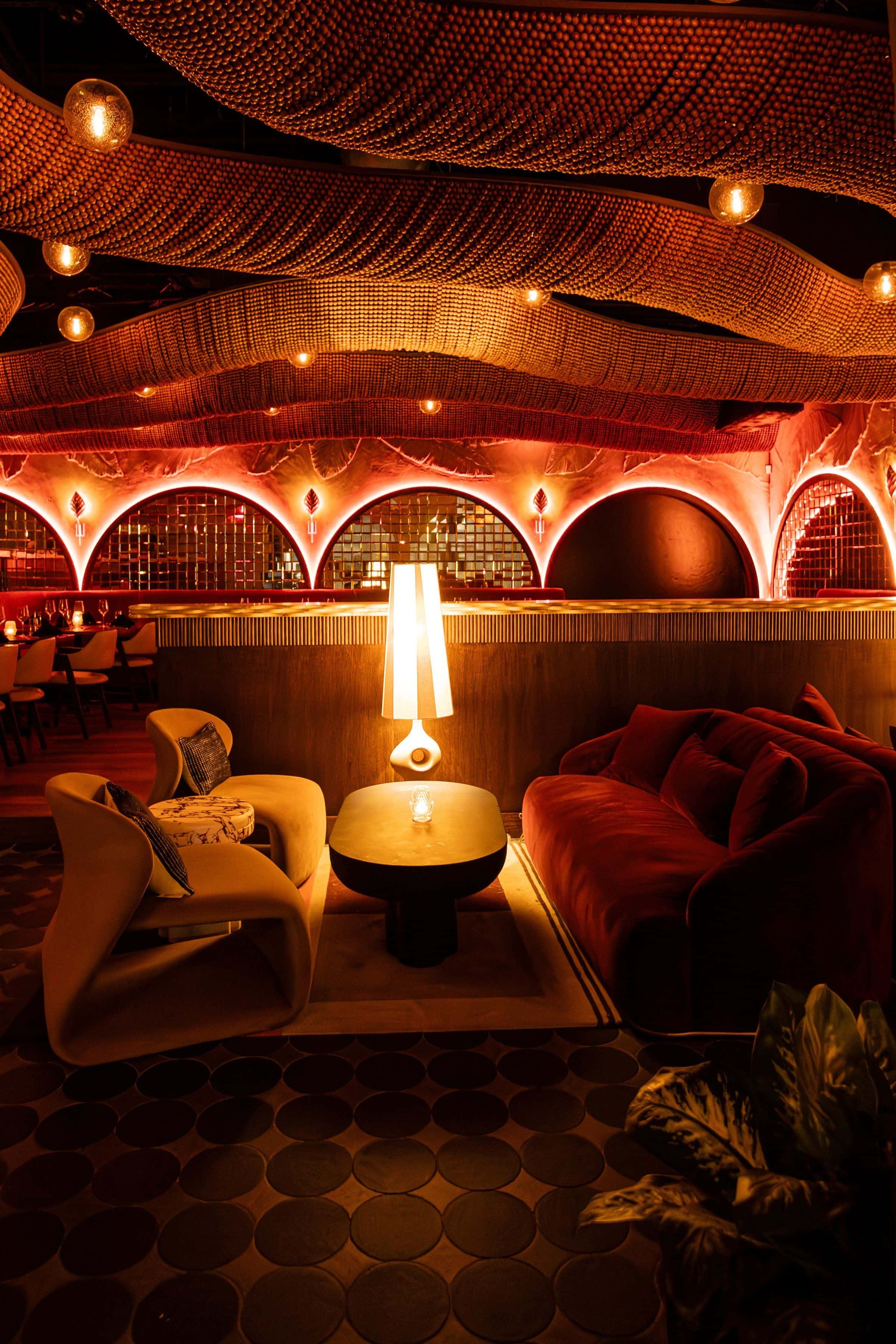 Lounge corner at KIRA with a glowing table lamp under red-lit arches